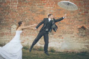 Spielerisches Hochzeitsfoto von fliegendem Regenschirm