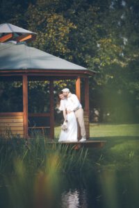 Hochzeitsfotografie Ehepaar vor braunen Holzhütte im Wald